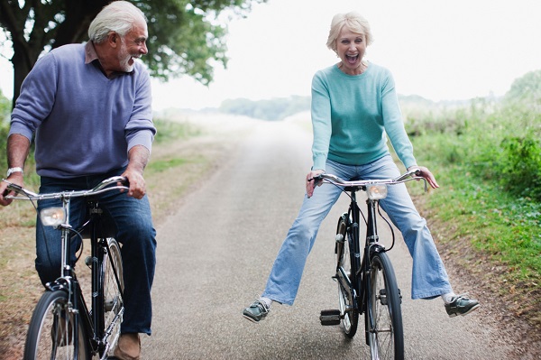 elderly couple riding bicycles and laughing