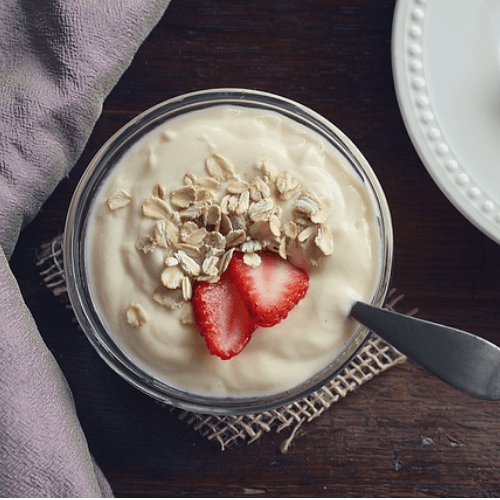 a nutritious vanilla yoghurt with crushed nuts and sliced strawberries